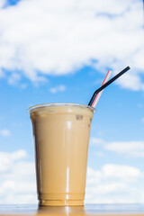 a iced coffee in takeaway cup in the background of blue sky