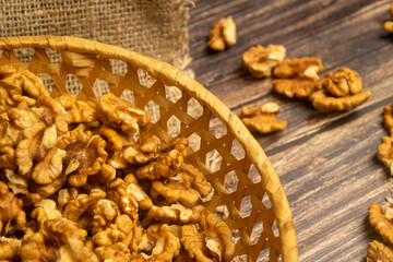 Peeled walnuts in a wicker basket and peeled walnuts scattered on a wooden table. Healthy diet. Fitness diet. Close up.