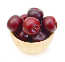 stack plum fruits in wooden bowl on white
