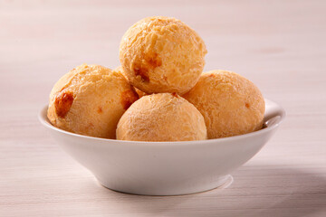 Brazilian cheese buns in white bowl on white wood background. Pao de queijo.