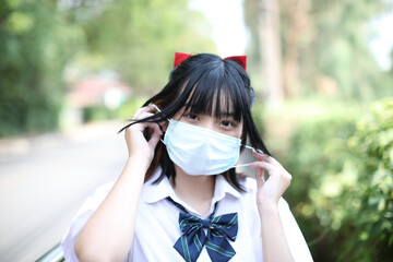 Asian school girl with mask in urban city on tree background