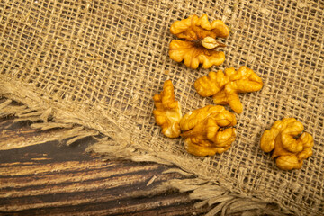 Peeled walnuts in bulk on a wooden table covered with rough-textured burlap. Healthy diet. Fitness diet. Close up.