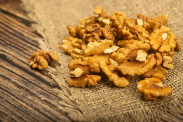 Peeled walnuts in bulk on a wooden table covered with rough-textured burlap. Healthy diet. Fitness diet. Close up.