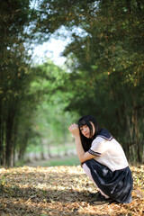 Portrait of beautiful Asian japanese high school girl uniform looking with bamboo forest background