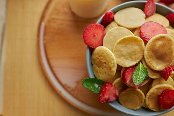Trendy breakfast cereal pancakes. Little pancakes. Breakfast pancakes with strawberries. Pancakes close-up top view.