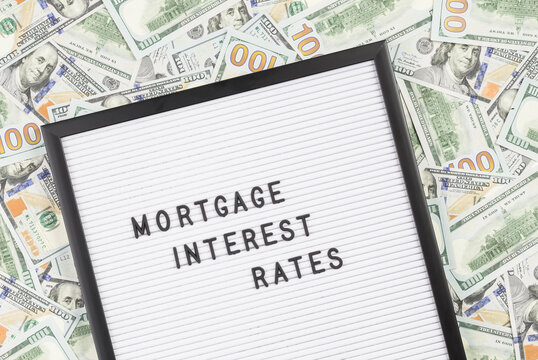 Mortgage interest rates text on letter board with lots of hundred dollar bills as background. Mortgage rates information banner or poster