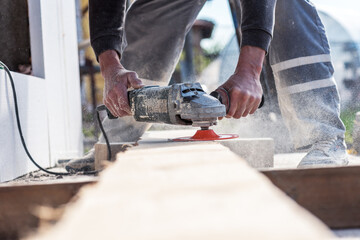 Man hands hold an old machine that grinds boards.