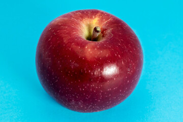 Close up of ripe red apple on blue background.