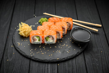 Sushi roll with salmon, cream cheese on black background.