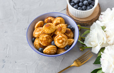Mini cereal pancakes with blueberries in a bowl on gray background. Trendy food concept, Breakfast time for kids. Menu, recipe