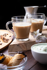 cup of coffee with sweets for coffee served at wooden tray at black wooden table.  against black background.  lifestyle concept