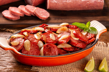 Smoked sausage with bread and onions on wood background. Snack appetizer calabrese sausage with onion.
