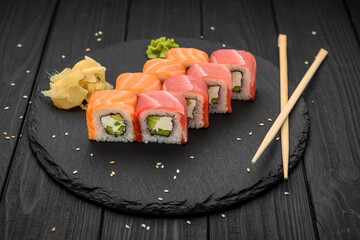 Sushi rolls with cheese philadelphia, salmon and tuna on a black background