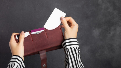 Mockup. A female hand holds a burgundy leather wallet with credit cards and takes out a blank...