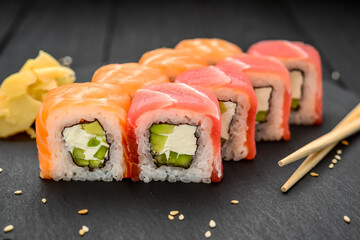 Sushi rolls with cheese philadelphia, salmon and tuna on a black background
