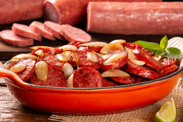 Smoked sausage with bread and onions on wood background. Snack appetizer calabrese sausage with onion.