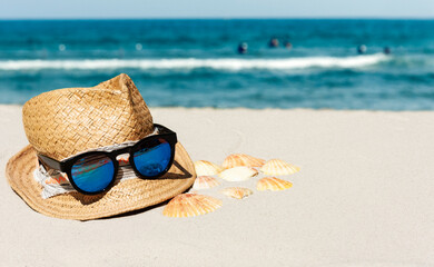 Vintage summer wicker straw beach hat and sunglasses on the beach near the sea.