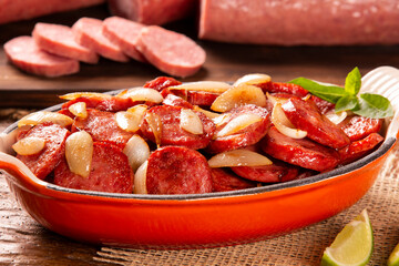 Smoked sausage with bread and onions on wood background. Snack appetizer calabrese sausage with onion.