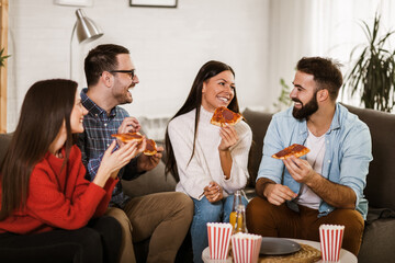 Group of young friends eating pizza in home interior.  Young people having fun together.