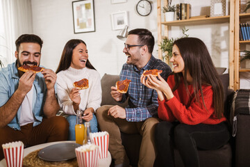 Group of young friends eating pizza in home interior.  Young people having fun together.
