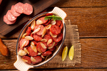 Smoked sausage with bread and onions on wood background. Snack appetizer calabrese sausage with onion.