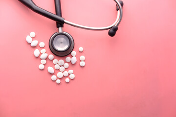  white pills and stethoscope on pink background 