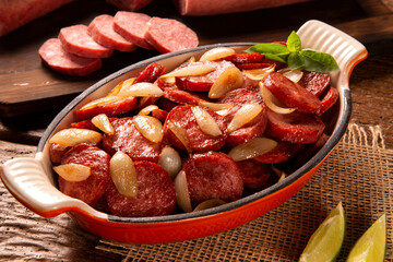 Smoked sausage with bread and onions on wood background. Snack appetizer calabrese sausage with...