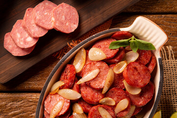 Smoked sausage with bread and onions on wood background. Snack appetizer calabrese sausage with onion.