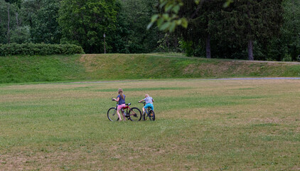 Teenagers ride bicycles in a city park. Recreation. Summer.