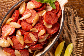 Smoked sausage with bread and onions on wood background. Snack appetizer calabrese sausage with onion.