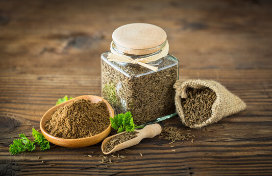 Fresh cumin seeds and powder on the wooden table