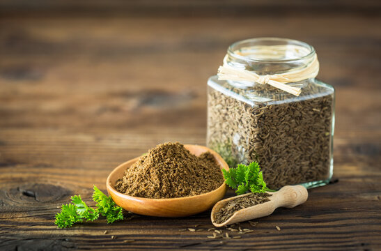 Fresh cumin seeds and powder on the wooden table