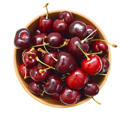 fresh cherries on wooden bowl over white