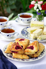 Afternoon tea in the garden with scones, strawberry jam, finger sandwiches with cucumber and egg salad.