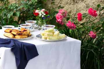 Afternoon tea in the garden with scones, strawberry jam, finger sandwiches with cucumber and egg salad.
