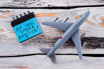 Do you speak english. Toy passanger air plane on white wood.