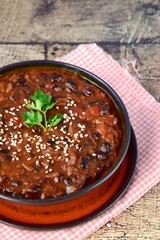 Homemade vegan chili black bean tomato soup garnish with sesame seeds and chopped parsley 