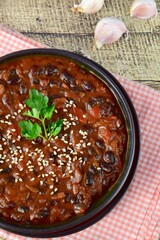 Homemade vegan chili black bean tomato soup garnish with sesame seeds and chopped parsley 