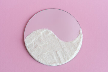 Collagen protein powder on the surface of the mirror, like yin yang on a pink background. Extra protein intake. Flatlay, top view.