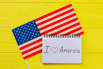 I love the united states of america. American flag and notepad on yellow wood.