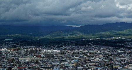 View of the edge of Hakodate, in northern Japan, with stormy mountains visible on the horizon