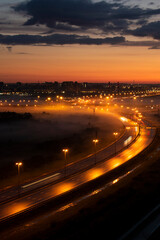 Fototapeta premium Night highway in the fog. Bright light from the headlights stretches along the road from a long exposure.