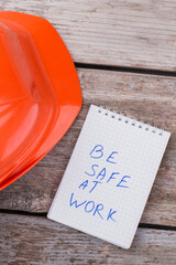 Be safe at work concept. Builder worker's helmet with notepad on the aged table.