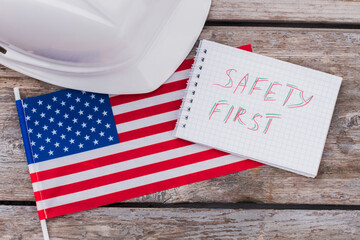 Safety of americal builders workers. Flag of the USA and notepad with helmet.