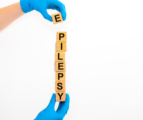 EPILEPSY word in doctor hands in gloves on white background with copy space. epilepsy cube concept
