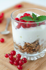 Light summer breakfast parfait with granola, vegan greek yogurt, redcurrant berries and garnished with basil leaves. Light and airy aesthetic