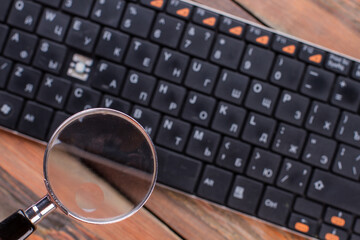 Fototapeta premium Magnifying glass over black keyboard. Missing key in the keyboard.