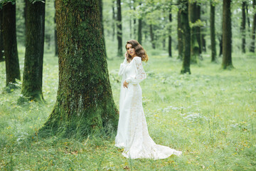 Obraz na płótnie Canvas Beautiful bride in fashion wedding dress on natural background.The stunning young bride is incredibly happy. Wedding day. A beautiful bride portrait in the forest.