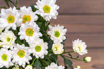 A bouquet of white bush chrysanthemums on a wooden table.