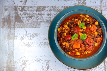 Black bean, quinoa, sweet potato, bell pepper and corn chili in a bowl garnish with parsley